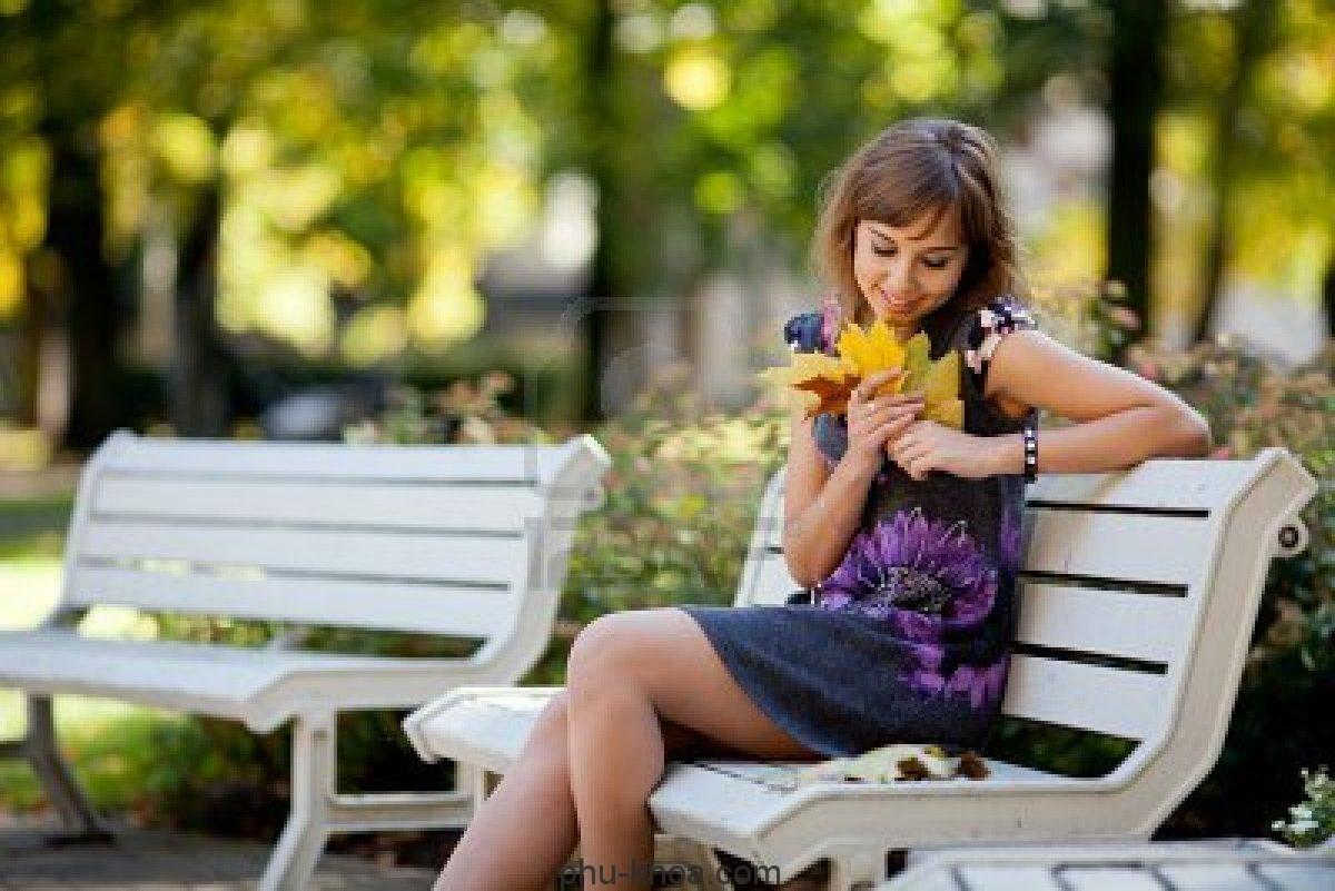 Женщина сидит в сиреневом саду на скамейке